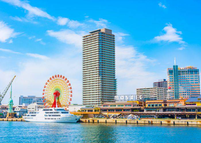 The Kobe Mosaic Harborland on a sunny day. A cruise ship is docked in front of the ferris wheel.